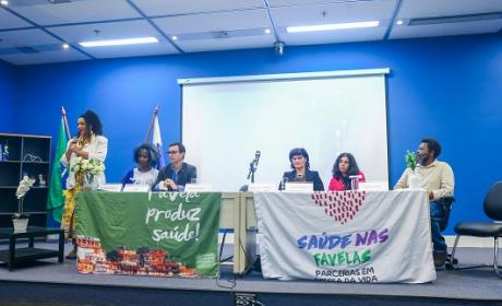 Foto de participantes à mesa do evento com bandeiras em exposição