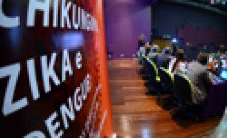 Foto do palco tirada por trás mostrando debaterdores e participantes do seminário