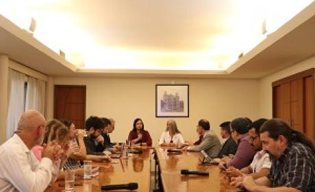 Dezenas de participantes de uma reunião sentados ao redor de uma mesa