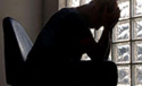 Sombra de homem sentado com as mãos na cabeça