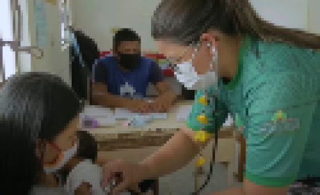 Médica examinando um bebê que está no colo da mãe